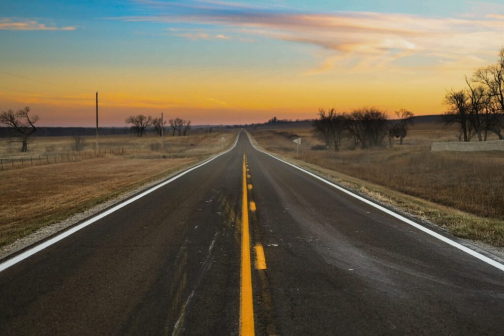 a long empty road in the middle of a field